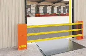 Barrera de seguridad retráctil de acero amarilla y naranja instalada en andén de carga, diseñada para prevenir caídas de vehículos, peatones y montacargas.